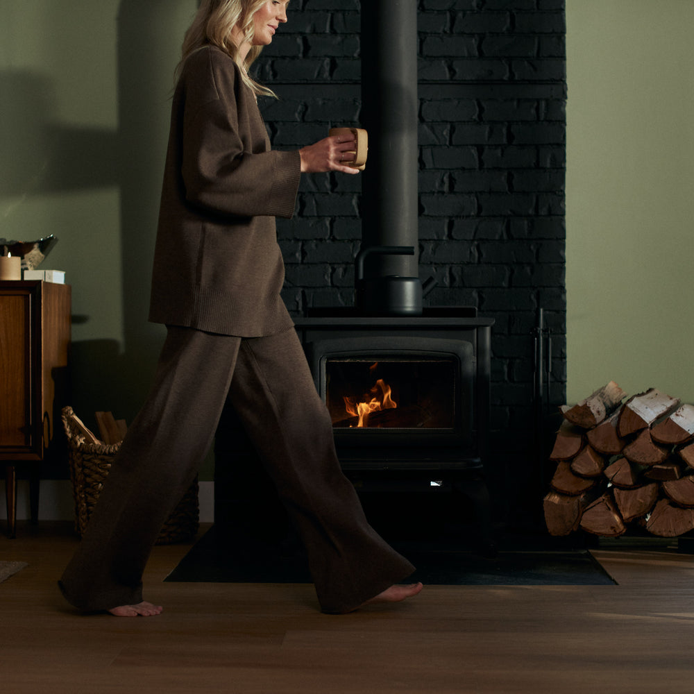 girl walking by fire holding a mug